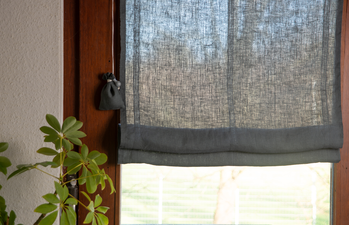 Graues Raffrollo aus stonewashed Leinen nach Maß am Fenster