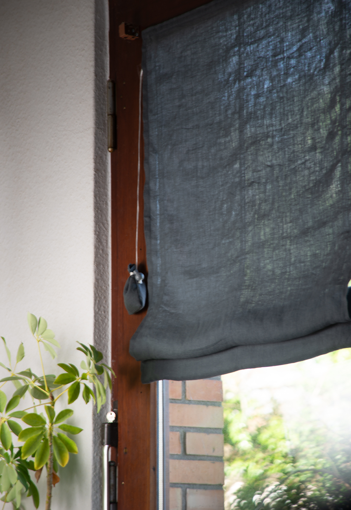 Anthrazit graues Raffrollo aus stonewashed Leinen nach Maß am Fenster